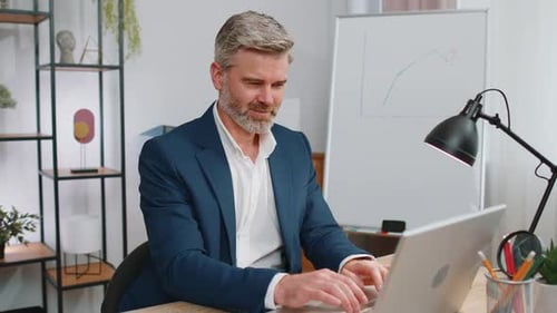 Mature Business Man Freelancer at Office Start Working on Laptop Computer Sends Online Messages