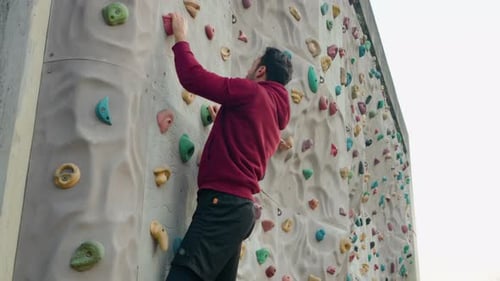 Young Man Climbing Colorful Outdoor Rock Climbing Wall