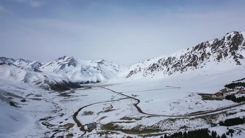 Aerial view drone flying over beautiful white snowy mountains landscape and a cloudy sky.