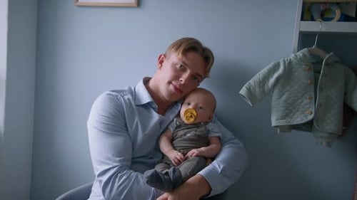 Porträt eines jungen Vaters, der einen kleinen Jungen wiegt