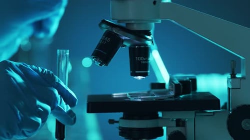 Gloved Hand Prepares Sample Under Microscope in Lab