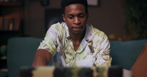 With a Laptop on a Table an African Man Chats Animatedly While Sitting on a Couch Language Exchange