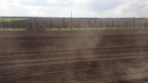 Blue tractror planting sunflower with yellow planter on the cultivated field in Ukraine