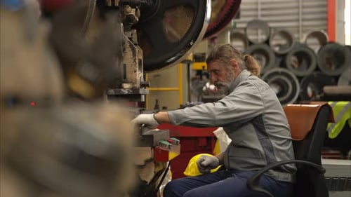 Senior experienced technician checking and maintenance a large machine in metal sheet factory