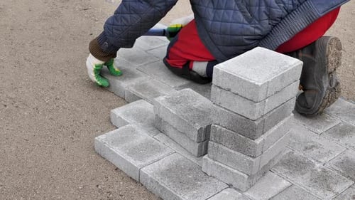 Worker Lays Gray Stone Bricks for Path
