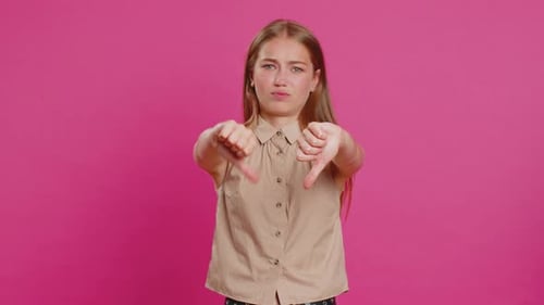 Woman Giving Thumbs Down on Pink Background