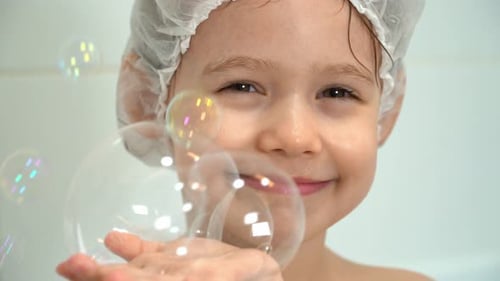 Smiling Child with Shower Cap Playing with Bubbles