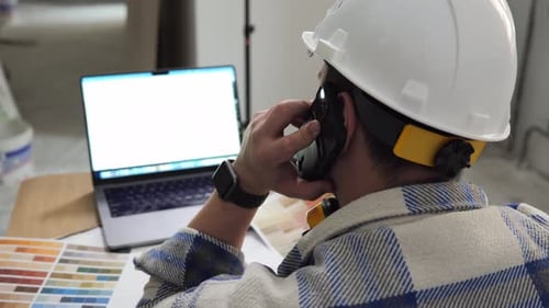 Architect Checks Drawings Using a Laptop and Talks on the Phone