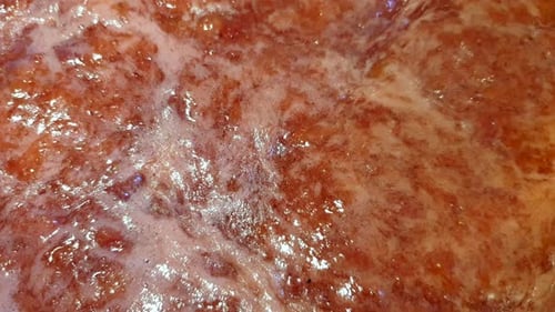 Close up of delicious homemade strawberry jam preserve gently simmering and cooking in a pot