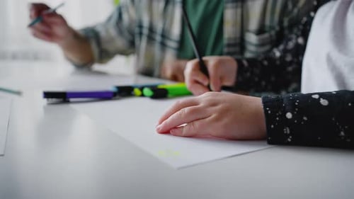 Children Drawing Together at White Table Indoors