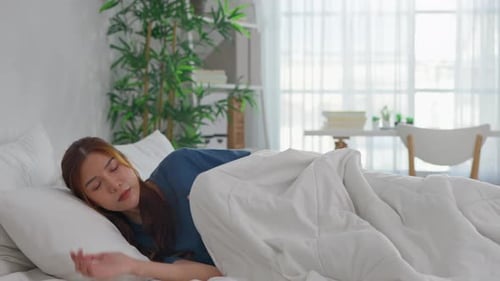 Young Woman Getting Into Bed for a Nap