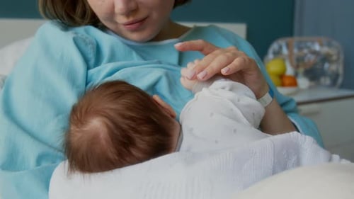 New Mother Holding Newborn Baby in Hospital Bed