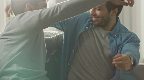 Two men embracing indoors sitting on couch