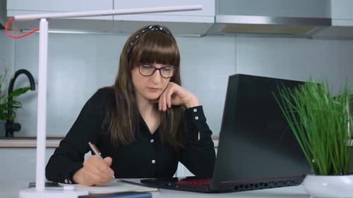 Empresária profissional trabalha no escritório doméstico no laptop enquanto faz anotações no Daily Planner