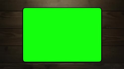 The tablet is lifted above the table, turning the display towards the viewer. green screen