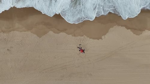 A Stunning Aerial View Showing a Vibrant Beach Gathering Surrounded By Waves and Colorful Umbrellas