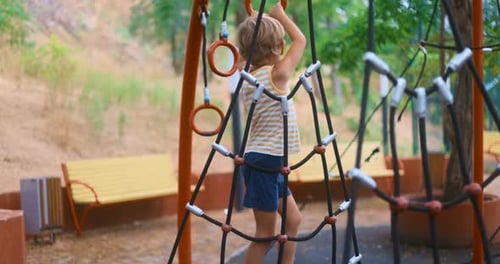 Child Climbing Rope Structure at Outdoor Playground