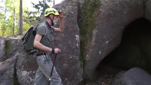 A Mature Male Adventurer with Hiking Equipment Exploring a Forest Cave