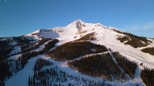 A drone shot of snowy Big Sky, Montana in winter, showcasing the ski resort and majestic mountain te