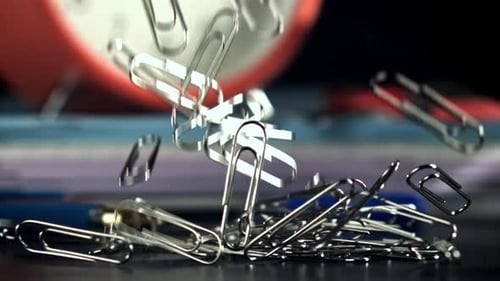 Paper Clips Falling on Desk with Pen and Documents