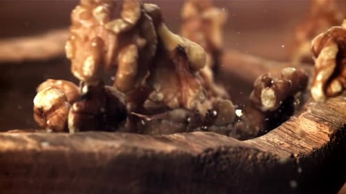 Walnuts falling into a wooden rustic bowl