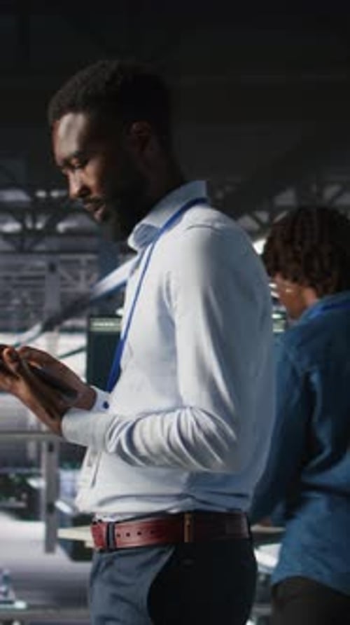 Vertical Video Technician Walks in Data Center Doing Maintenance Tasks on Tablet