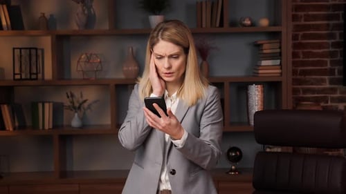 Worried Woman Looking at Her Phone in Office