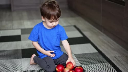 Cute Child Eating Apples in Home Kitchen
