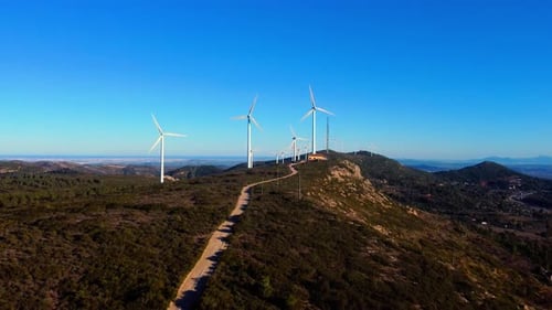 Aerial drone footage of a wind turbines on mountain ridges generating renewable energy.