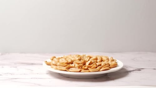 Side View of Hand Pick Peanuts From a Plate