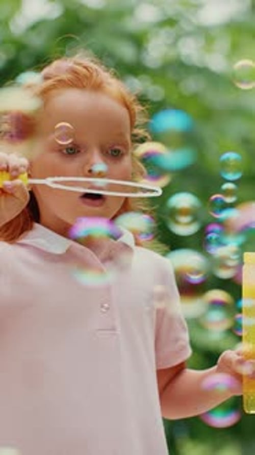 Child Blowing Bubbles in a Sunny Garden During Summer Afternoon