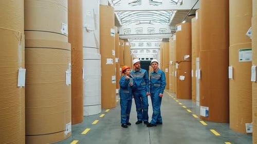 A Group of Paper Mill Workers Engineers Take Inventory of a Huge Warehouse with Rolls of Kraft Paper