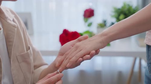 Nahaufnahme eines jungen Mannes, der seiner Freundin einen überraschenden Heiratsantrag macht.