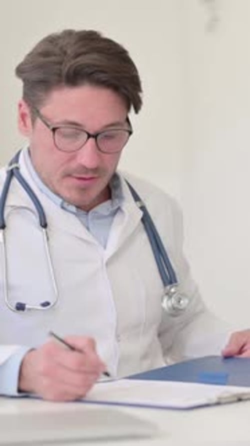 Doctor Writes on Chart and Hands to Patient