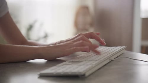Hands Typing on Keyboard at Desk