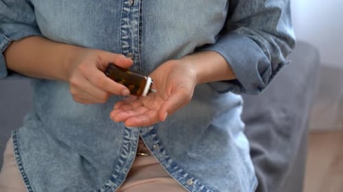 Adult Pours Pills From Bottle Into Hand