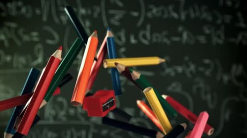 Multicolored Pencils Flying Against the Background of a Blackboard Filmed on a Highspeed Camera at