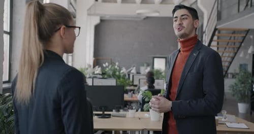 Middle Eastern Man and Caucasian Woman Talking Shaking Hands Standing in Shared Office