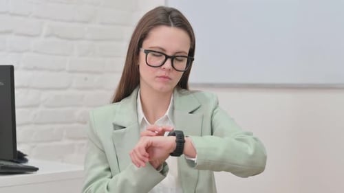Young Woman Interacting with Smart Watch at Desk