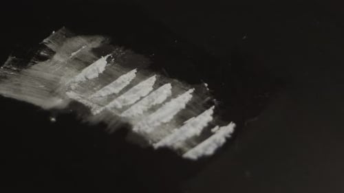 Lines of cocaine powder lying on black table - medium high angle view