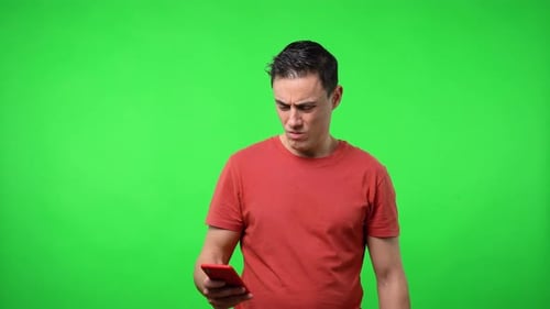 Man Looks at His Phone on Green Background