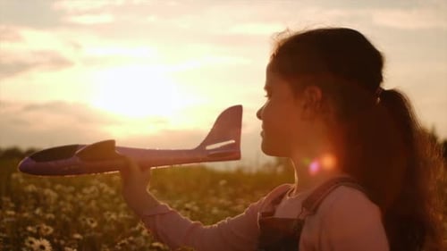 Girl Plays with Airplane Toy in Sunset Meadow