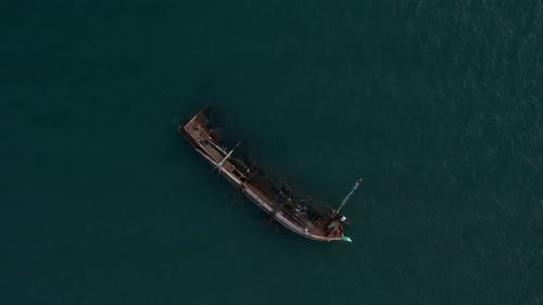 Top View Of A Boat Sinking Into The Blue Waters
