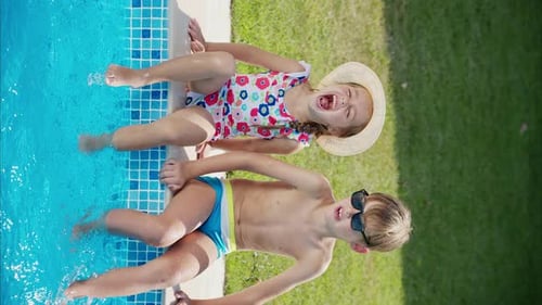 Little boy and sister girl playing in a pool, making water splashes, slow motion vertical screen