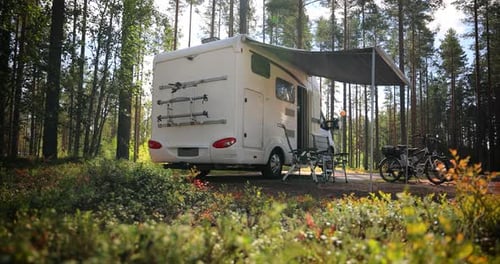 RV Parked in Sunny Forest with Bicycles