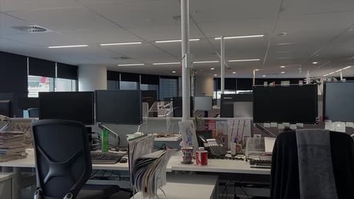High quality dolly shot over empty desks in a large and deserted office building with unattended wor