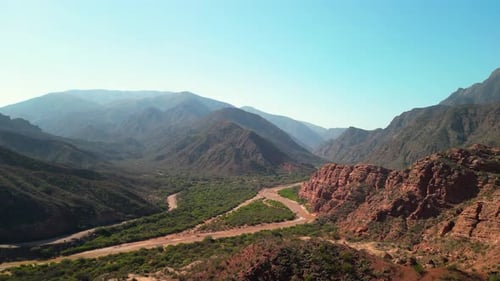 Aerial view drone flying over scenic red rocky mountains with a clear blue sky.