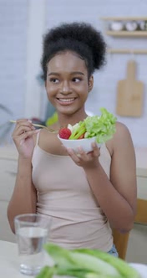 young african american female happily preparing to eat salad with fork holding bowl full of green