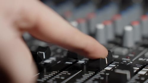 Sound engineer adjusting audio mixer controller for live music, close up