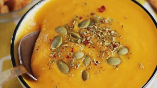 Cremige Gemüsesuppe mit Gewürzen und Kürbiskern Chef probiert Suppe mit einem Löffel